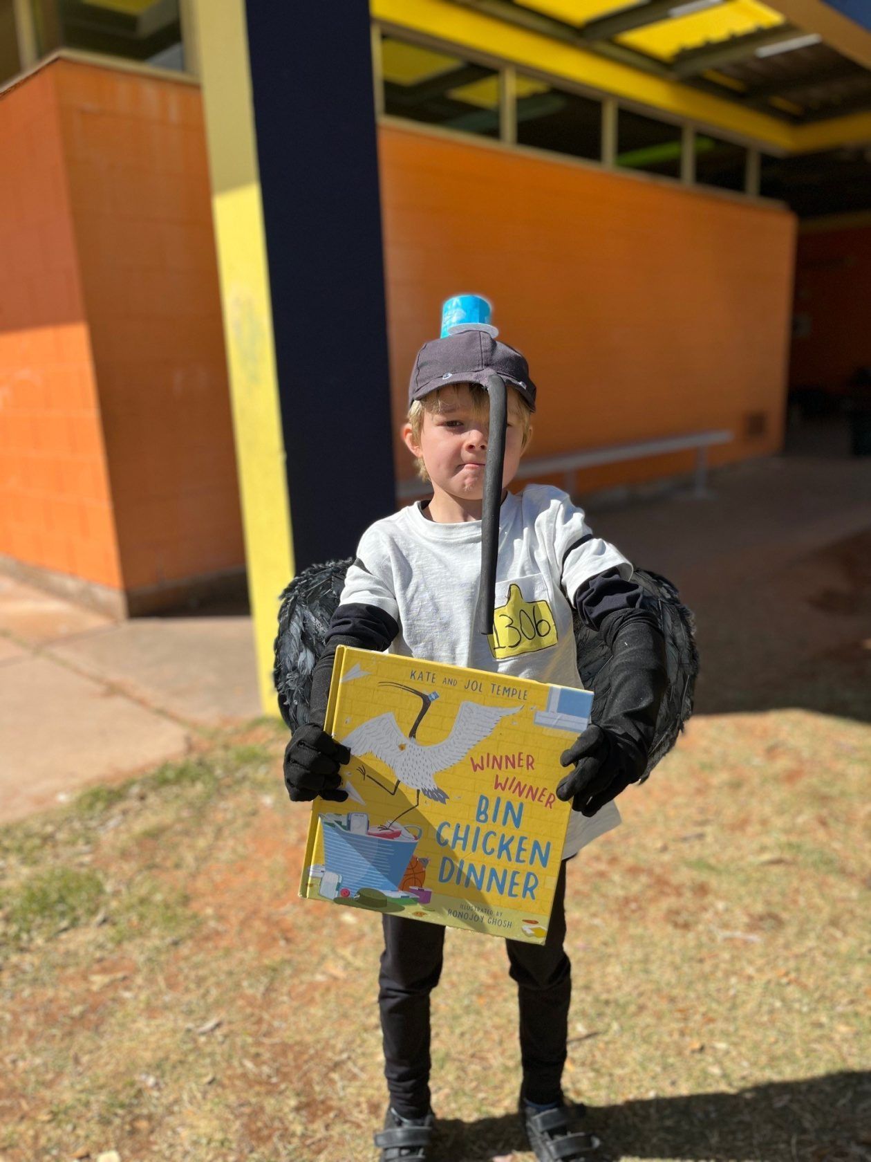 Child in a bird costume holding a book titled 