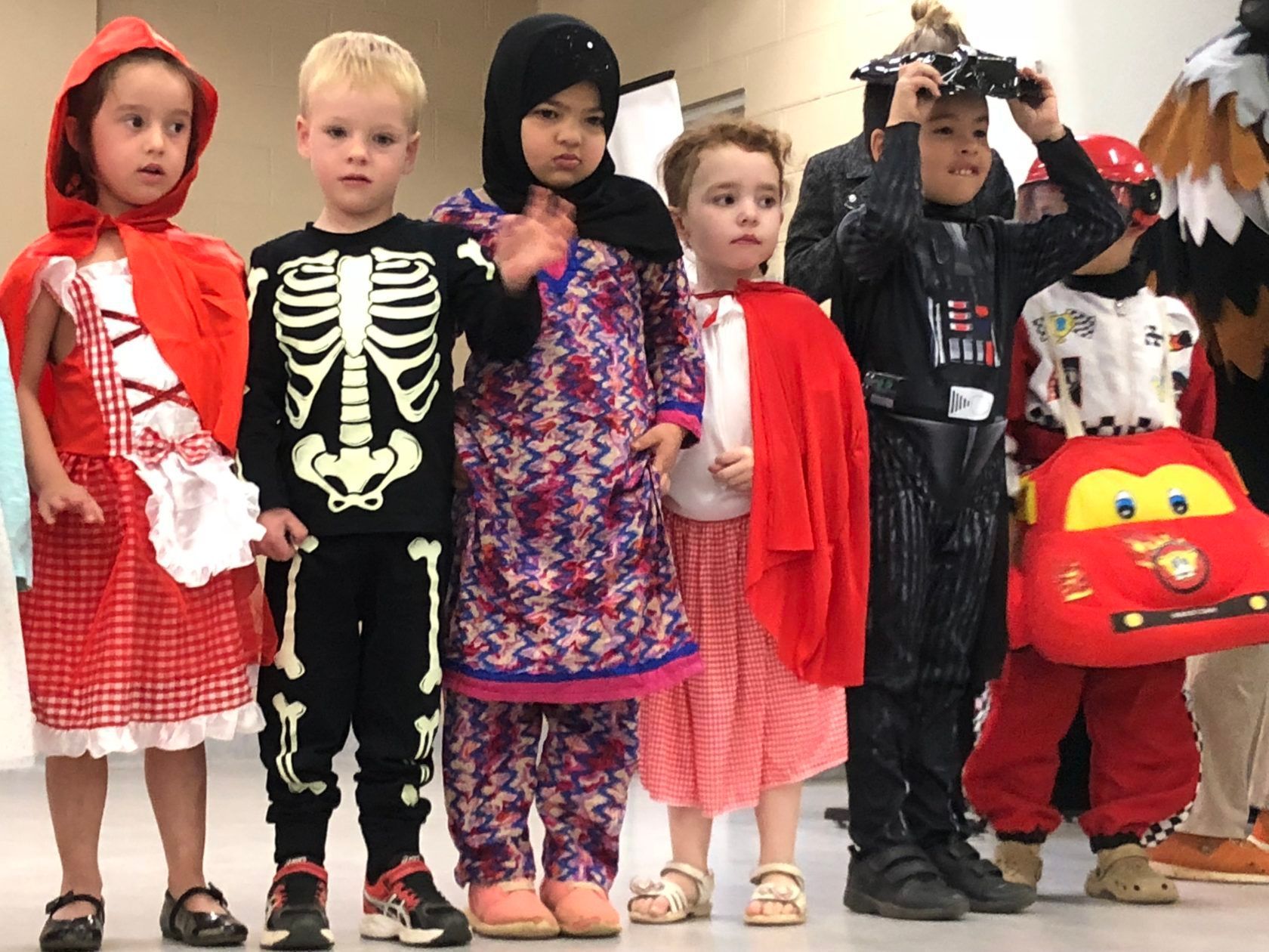Children in costumes: Red Riding Hood, skeleton, Muslim dress, red cape, Darth Vader, and a race car.