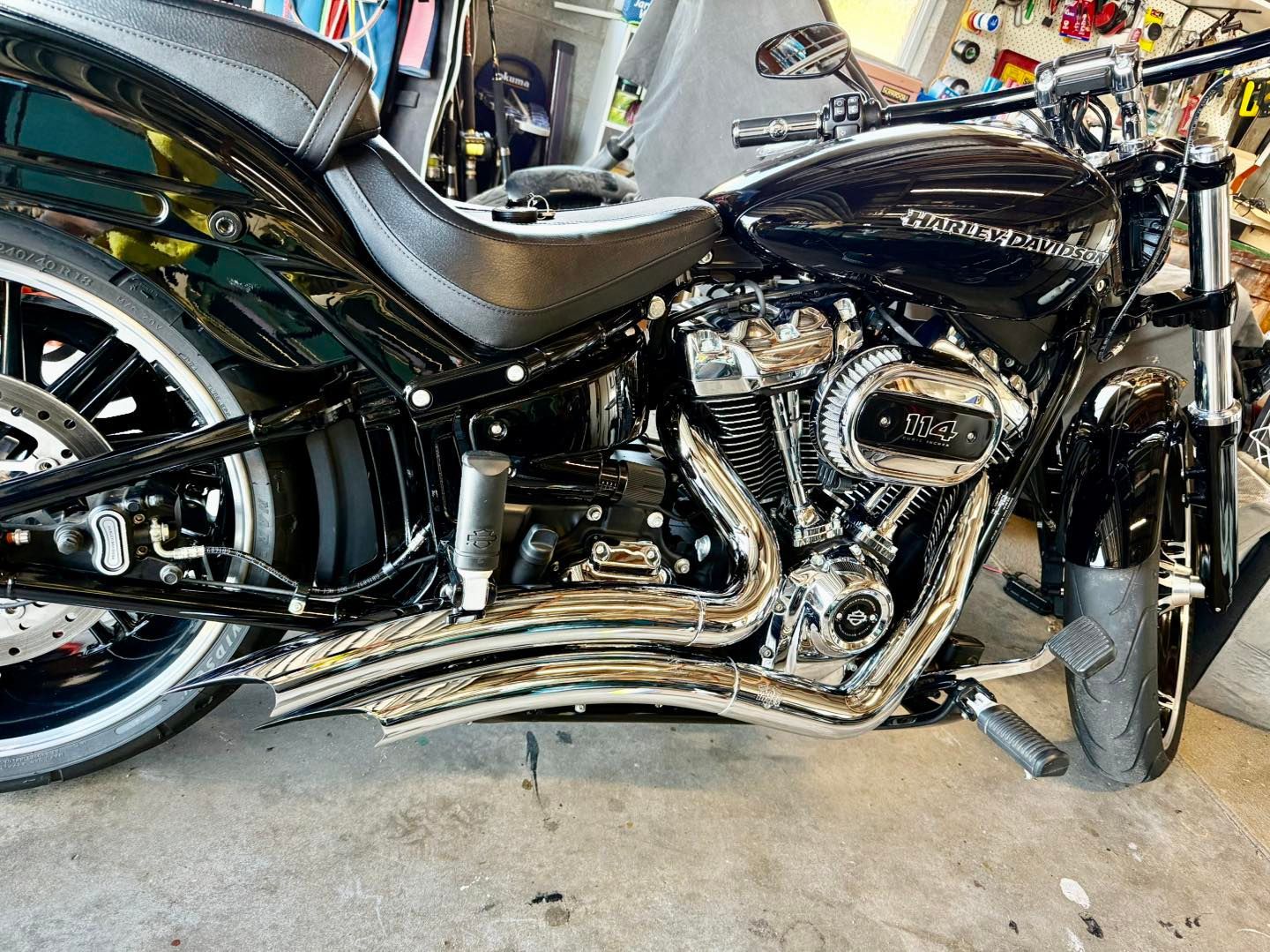 Black Harley-Davidson motorcycle with chrome accents, parked indoors, close-up side view.