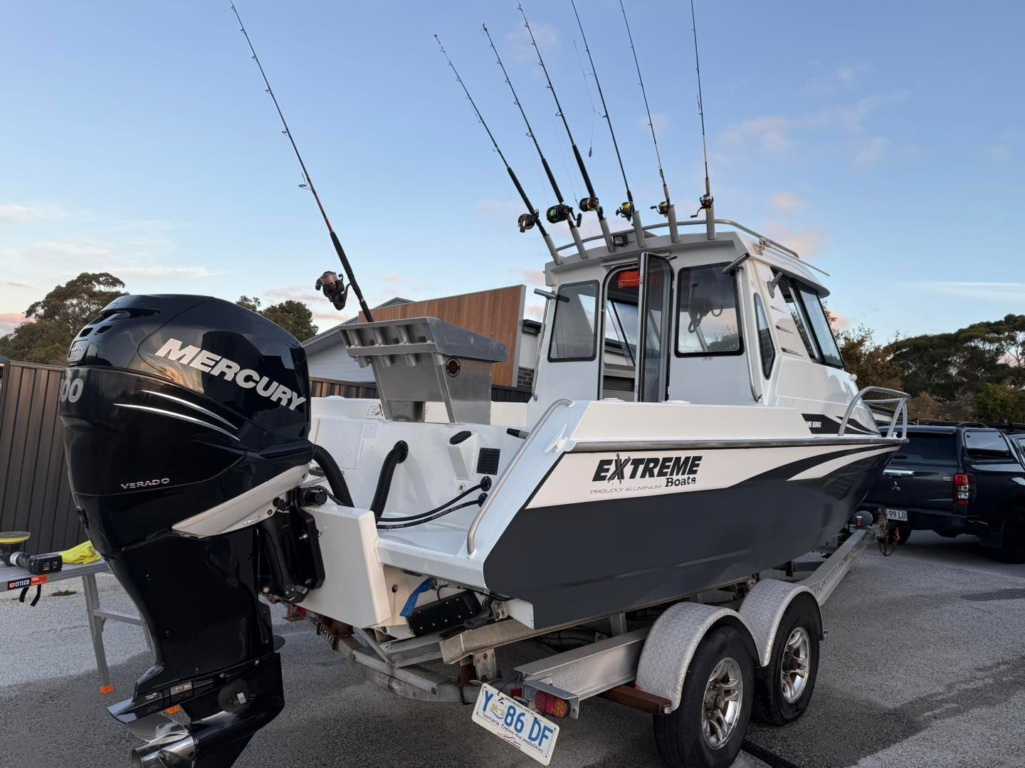 White and gray fishing boat on a trailer with a Mercury outboard motor, fishing rods, and 