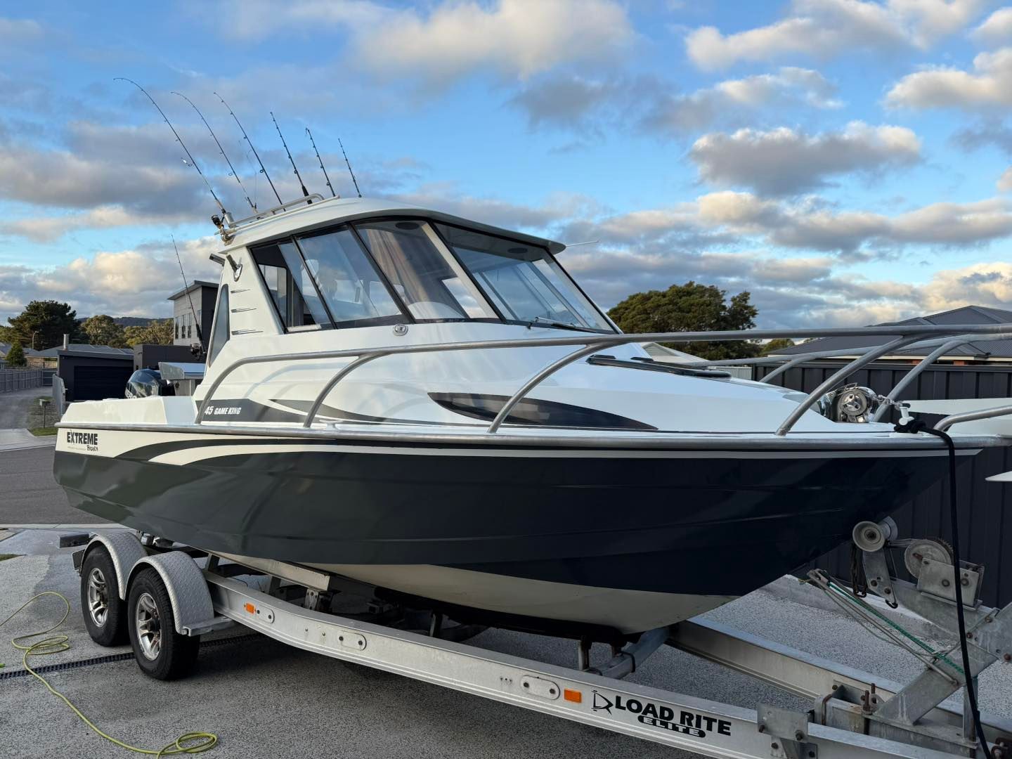 A grey and white boat on a trailer, ready for the water, under a cloudy sky.