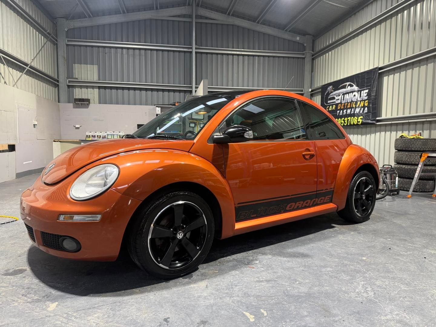 Person polishes a white car with a yellow and black polisher, near the gas tank door.