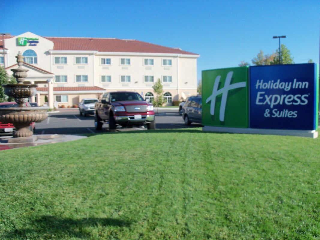 Holiday Inn Express & Suites with cars in front; green lawn.