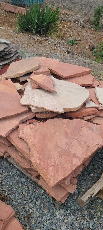 Pile of irregularly shaped red sandstone flagstones.