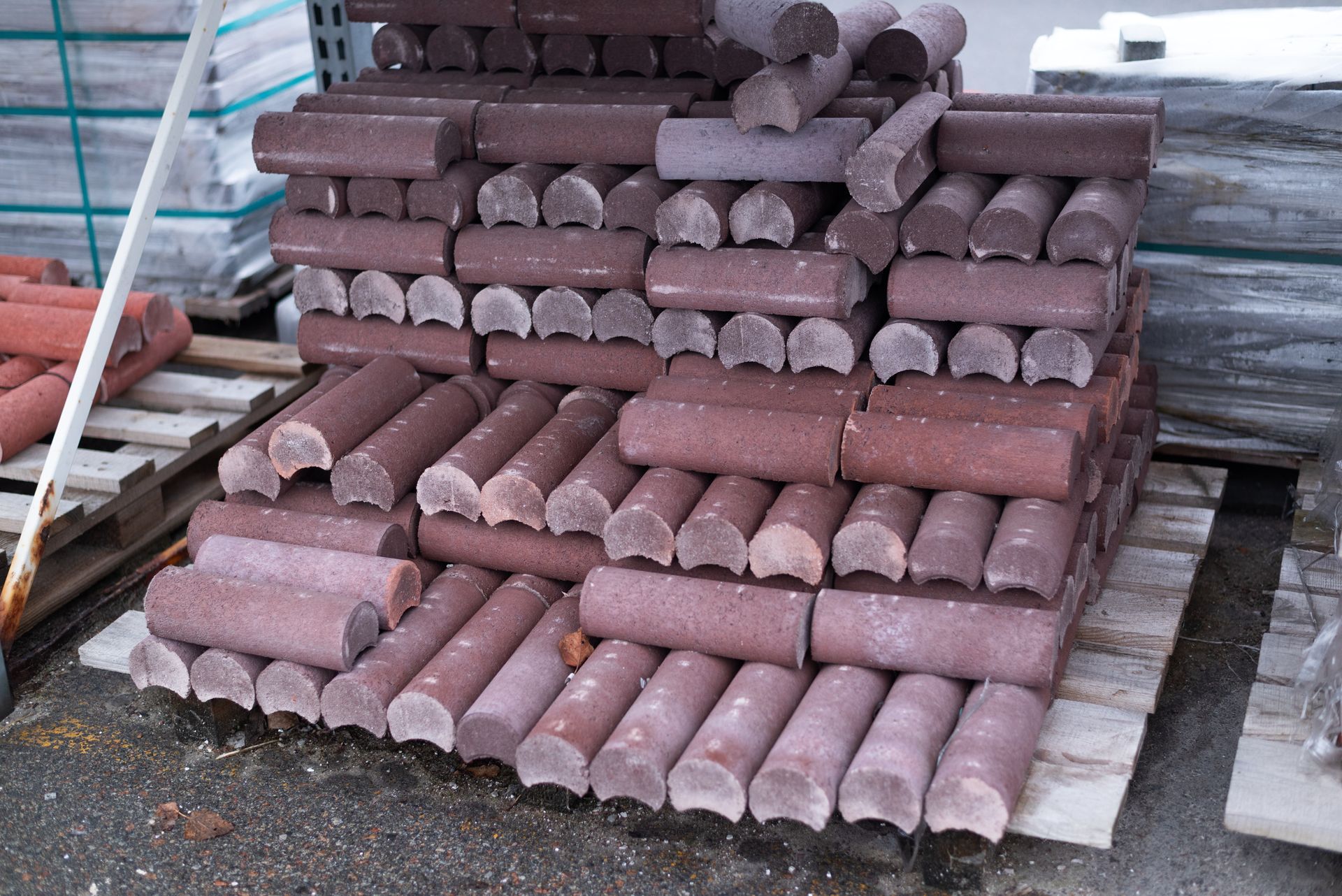 Pile of reddish-brown concrete edging stones stacked on a wooden pallet outdoors.
