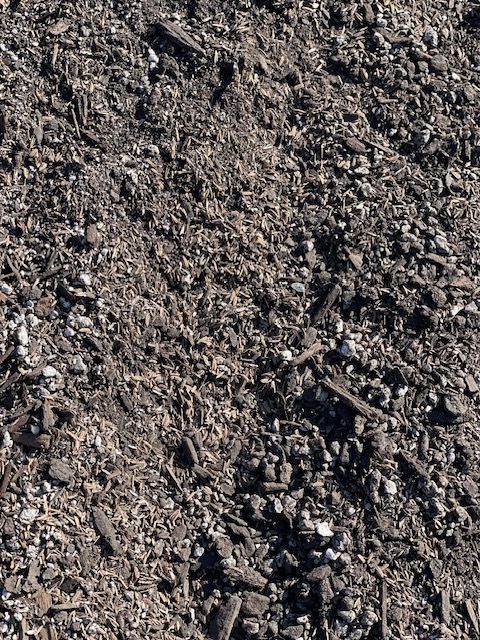 Close-up of dark brown mulch with small wood chips and white pebbles.