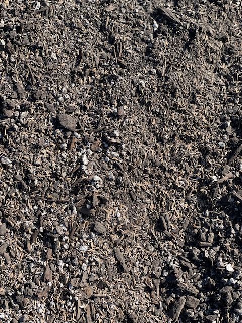 Close-up of dark brown mulch with flecks of lighter-colored organic material.