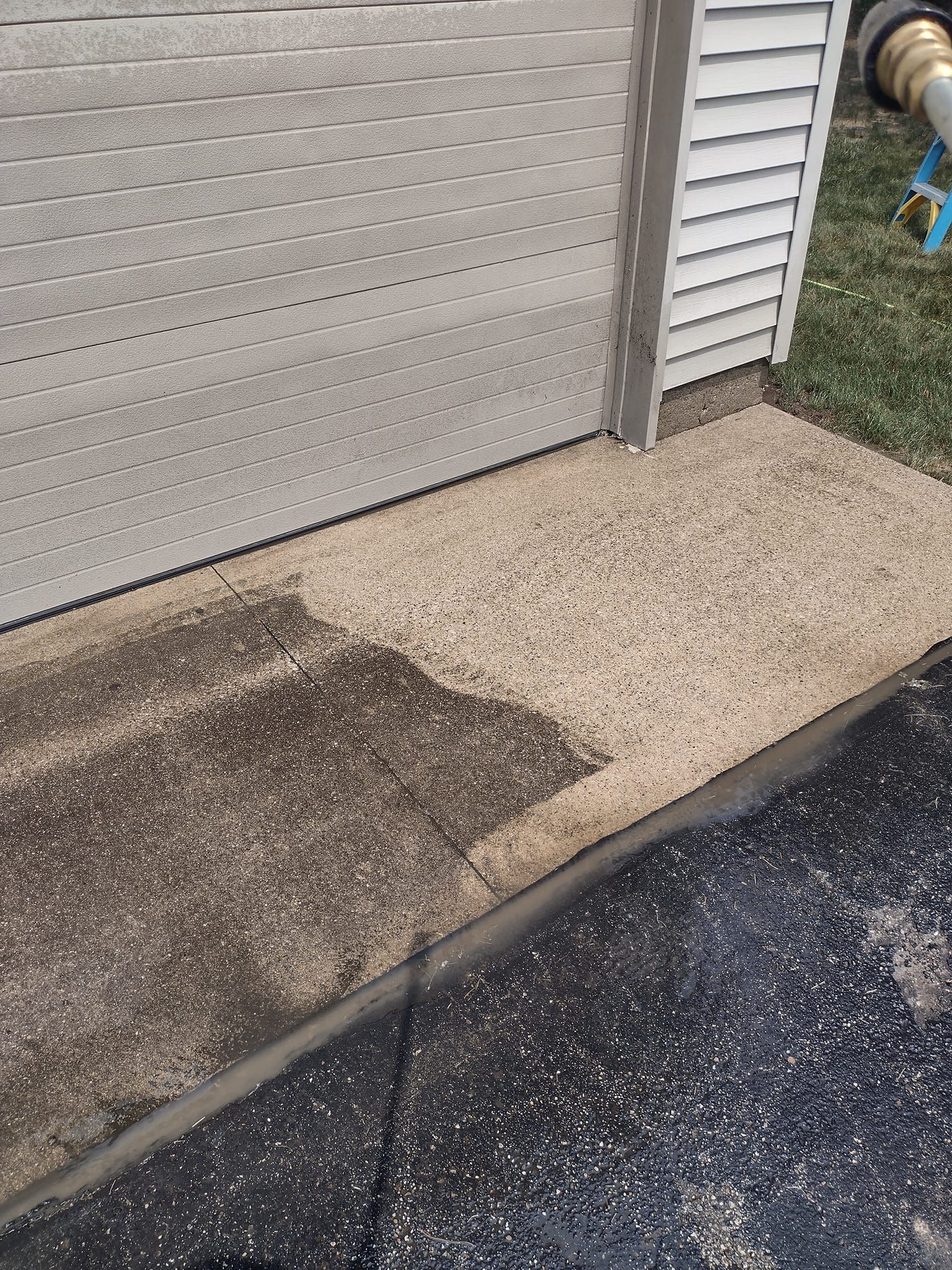 Concrete sidewalk with dark stains, next to a textured wall and asphalt.