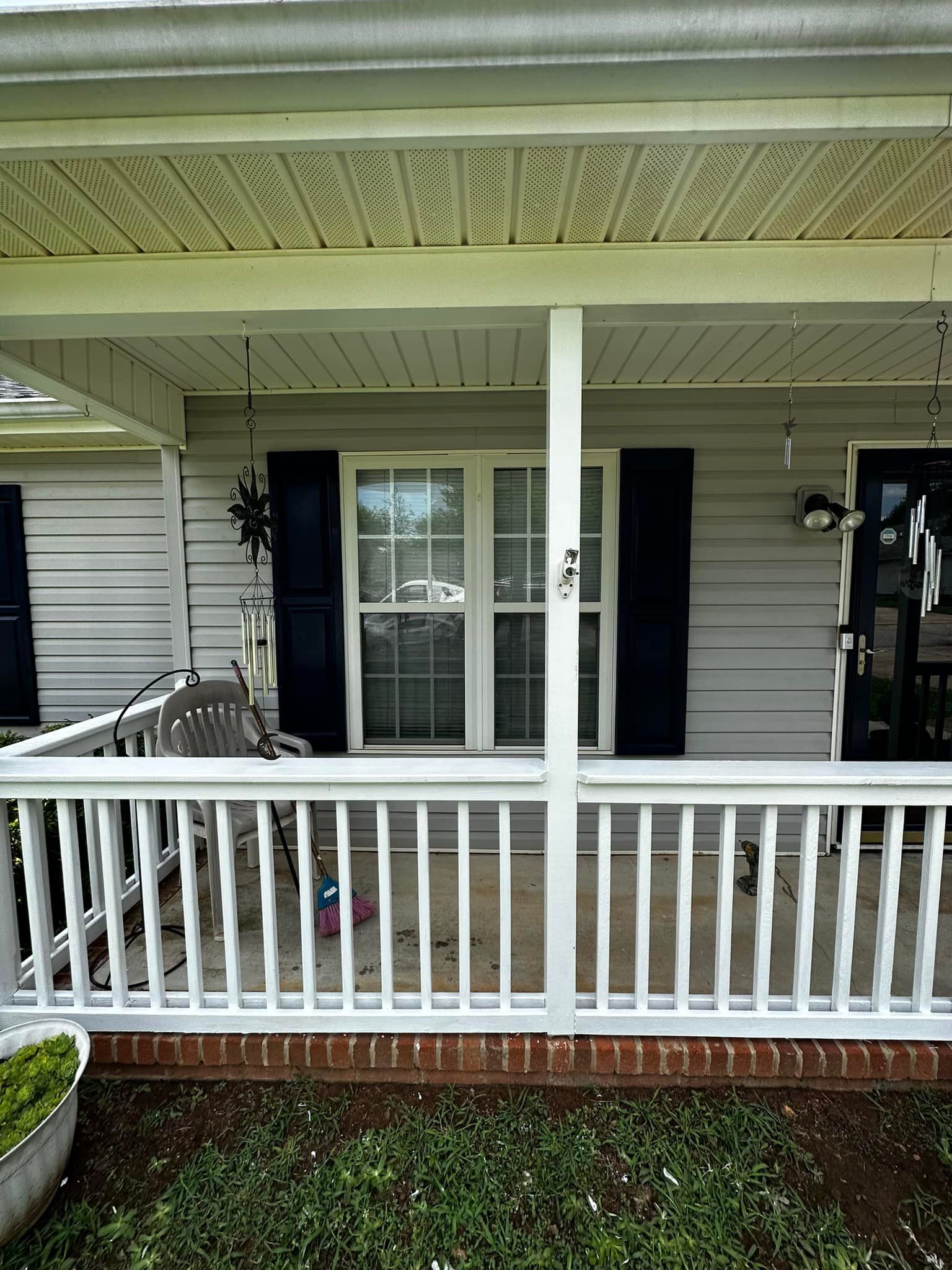 White porch with railing, shutters, and window; house siding in the background.