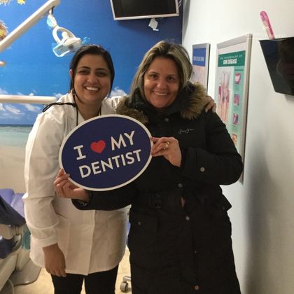 female patient holding I love my dentist sign beside dentist