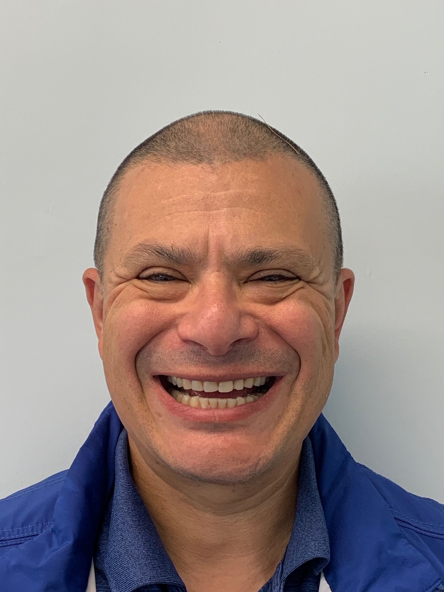 A man is smiling for the camera and wearing a blue jacket.