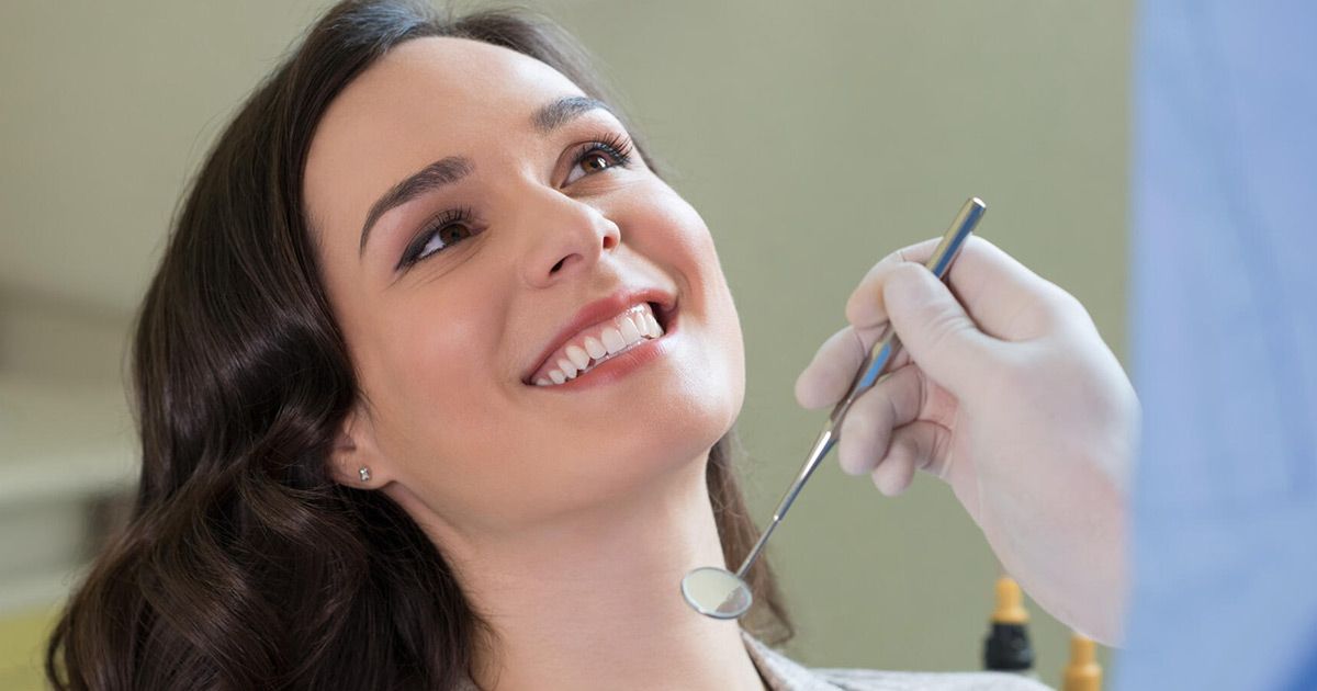 A woman is getting her teeth examined by a dentist.