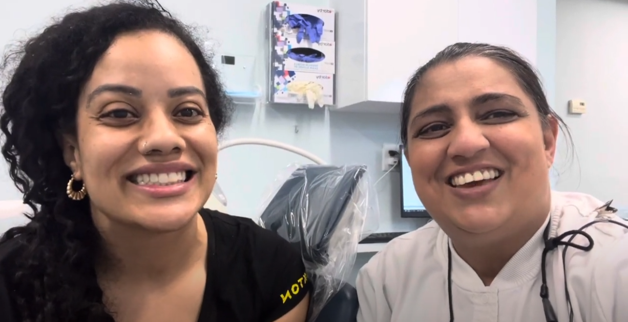 Two women are smiling for the camera in a dental office.