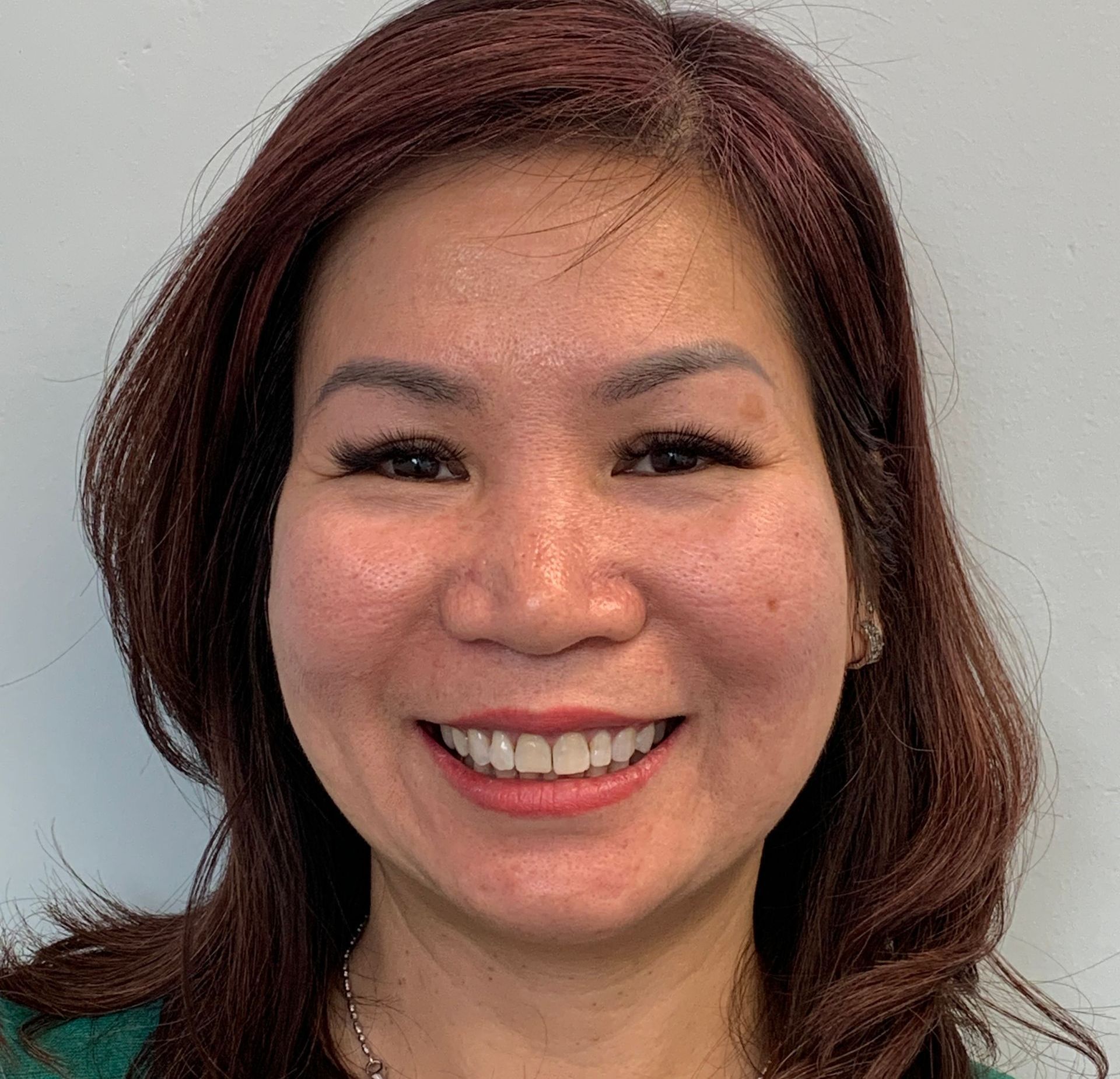 A woman with long brown hair is smiling for the camera.