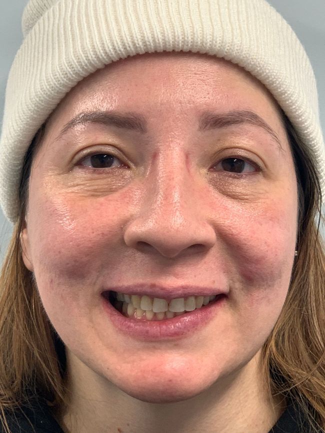 A close up of a woman wearing a beanie and smiling.