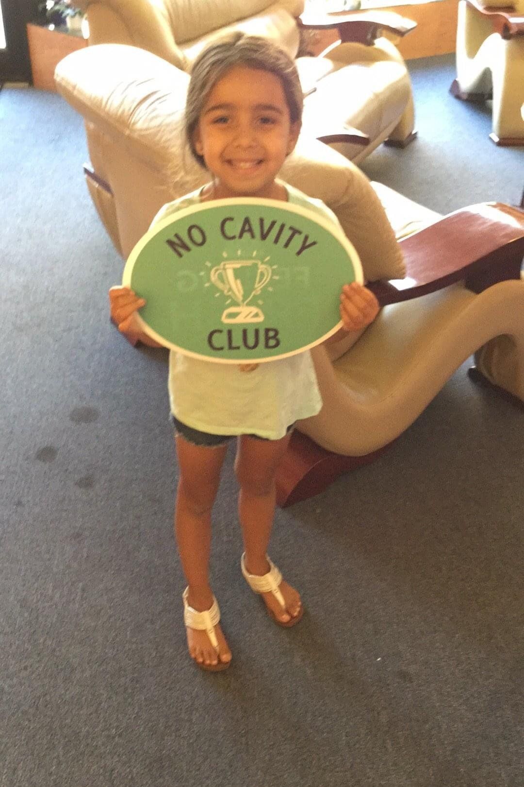 little girl holding no cavity club sign