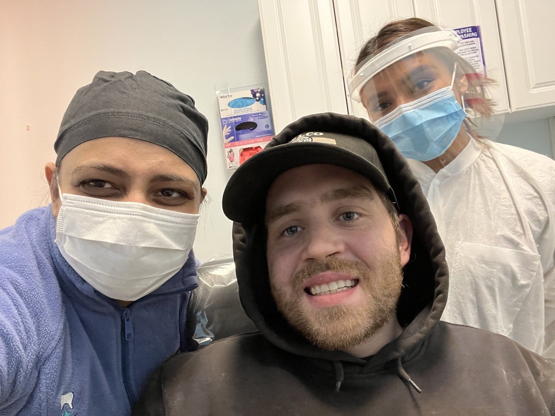 male patient smiling with 2 dentists