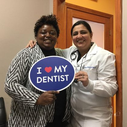 african female patient holding I heart dentist sign with dentist