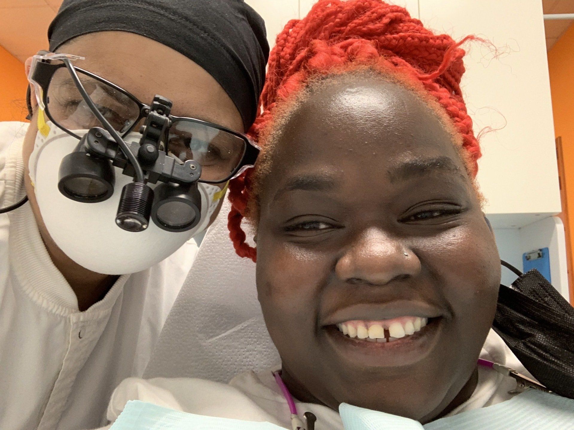 female african patient with orange color hair smiling with dentist