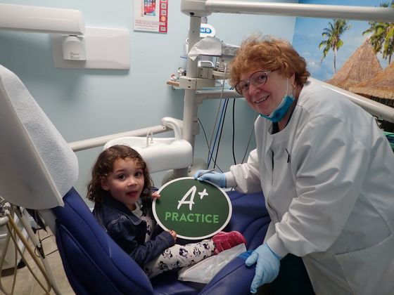 little girl holding A practice sign with dentist