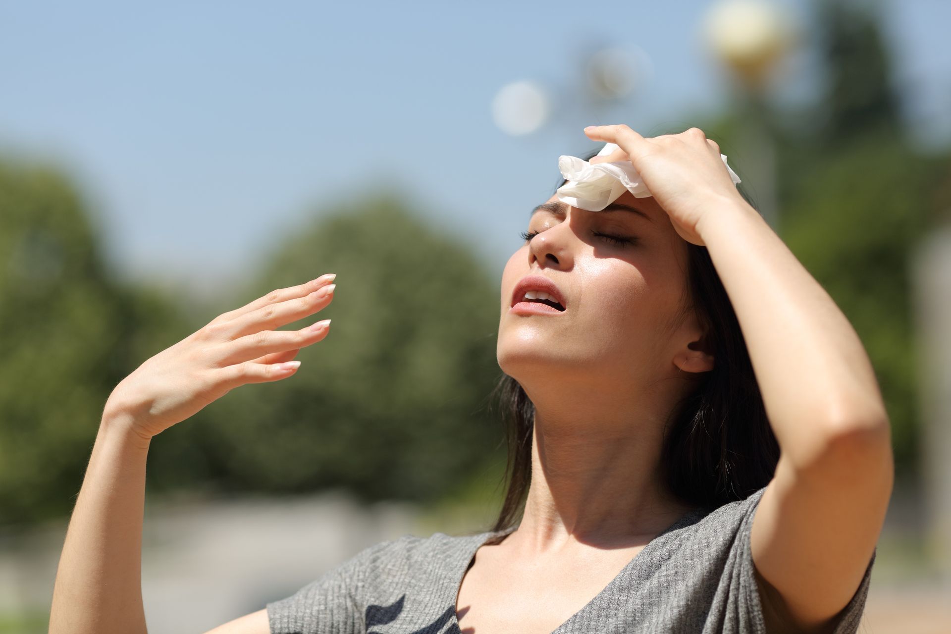A woman is wiping her forehead with a napkin.