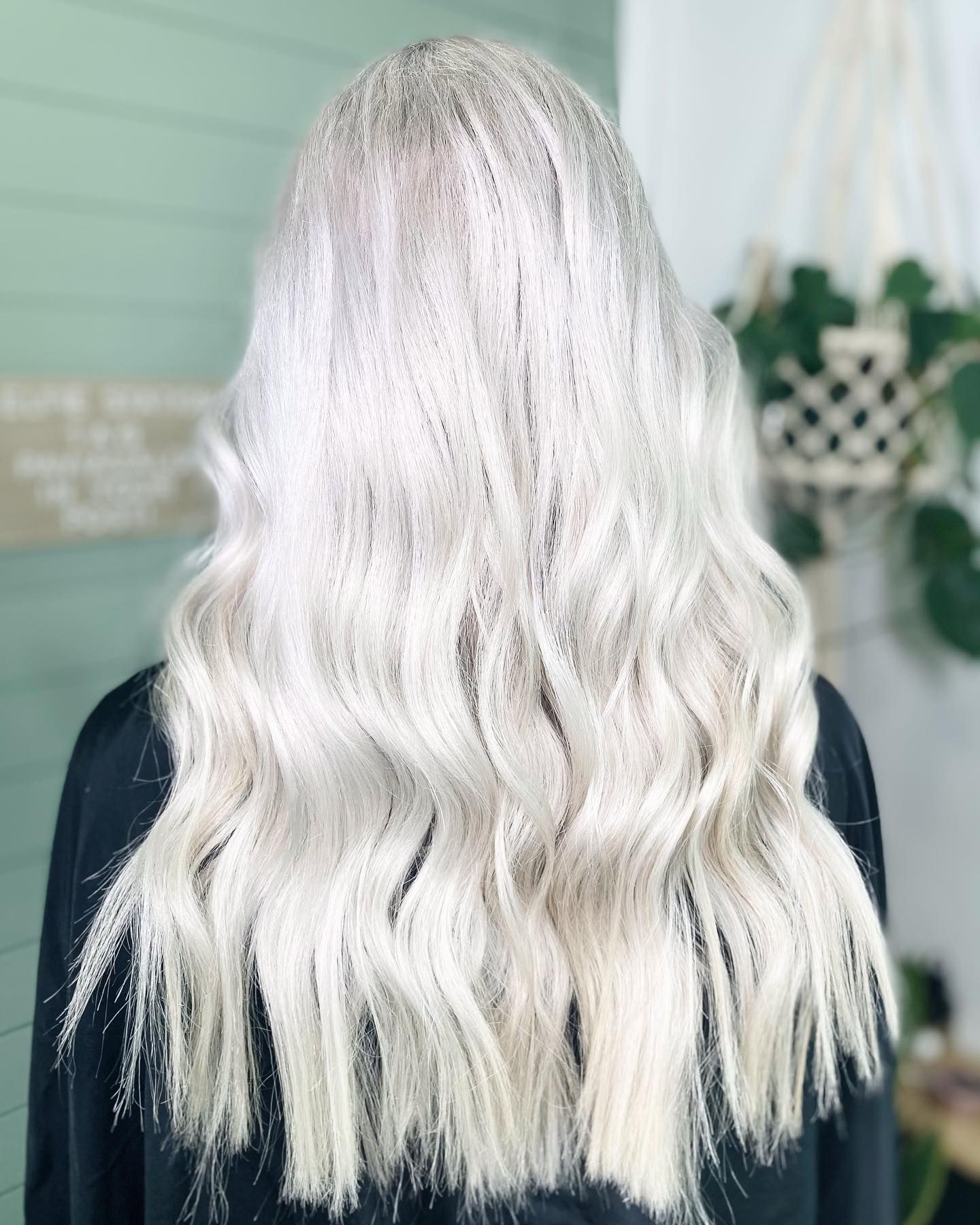 Woman with long, wavy, platinum blonde hair, back view.