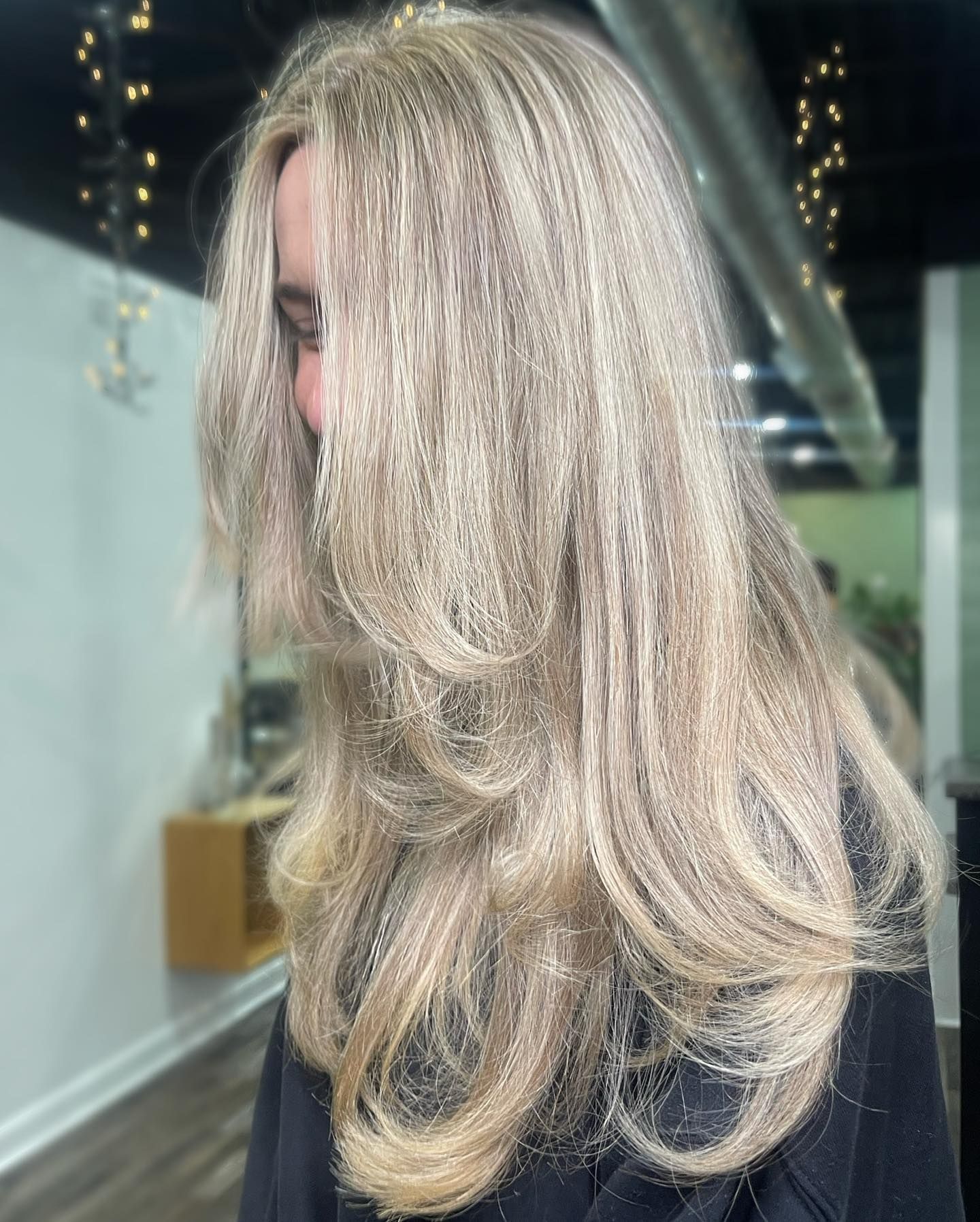 Woman with layered, long, blonde hair styled in a salon.
