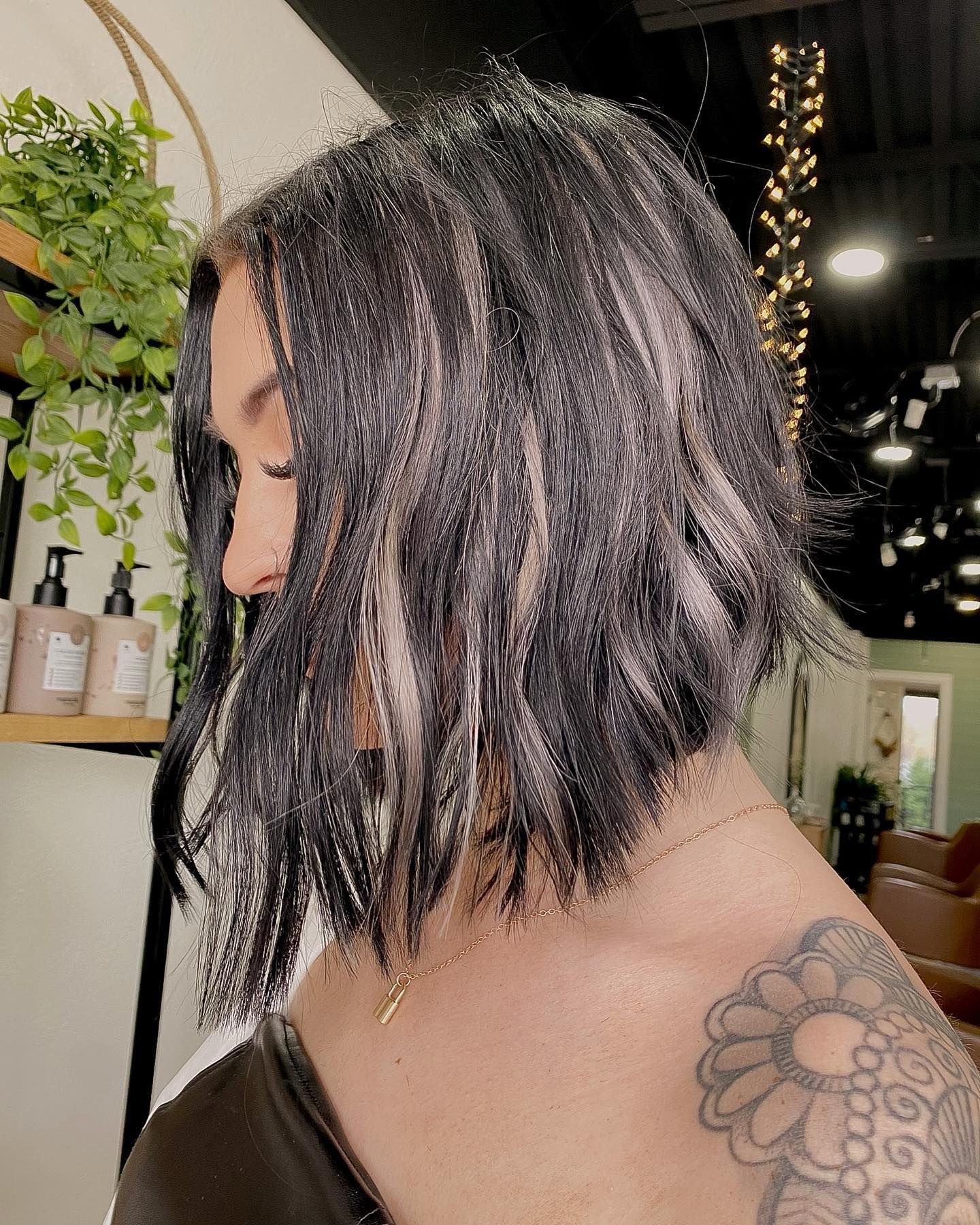 Woman with dark, layered bob haircut and shoulder tattoo.