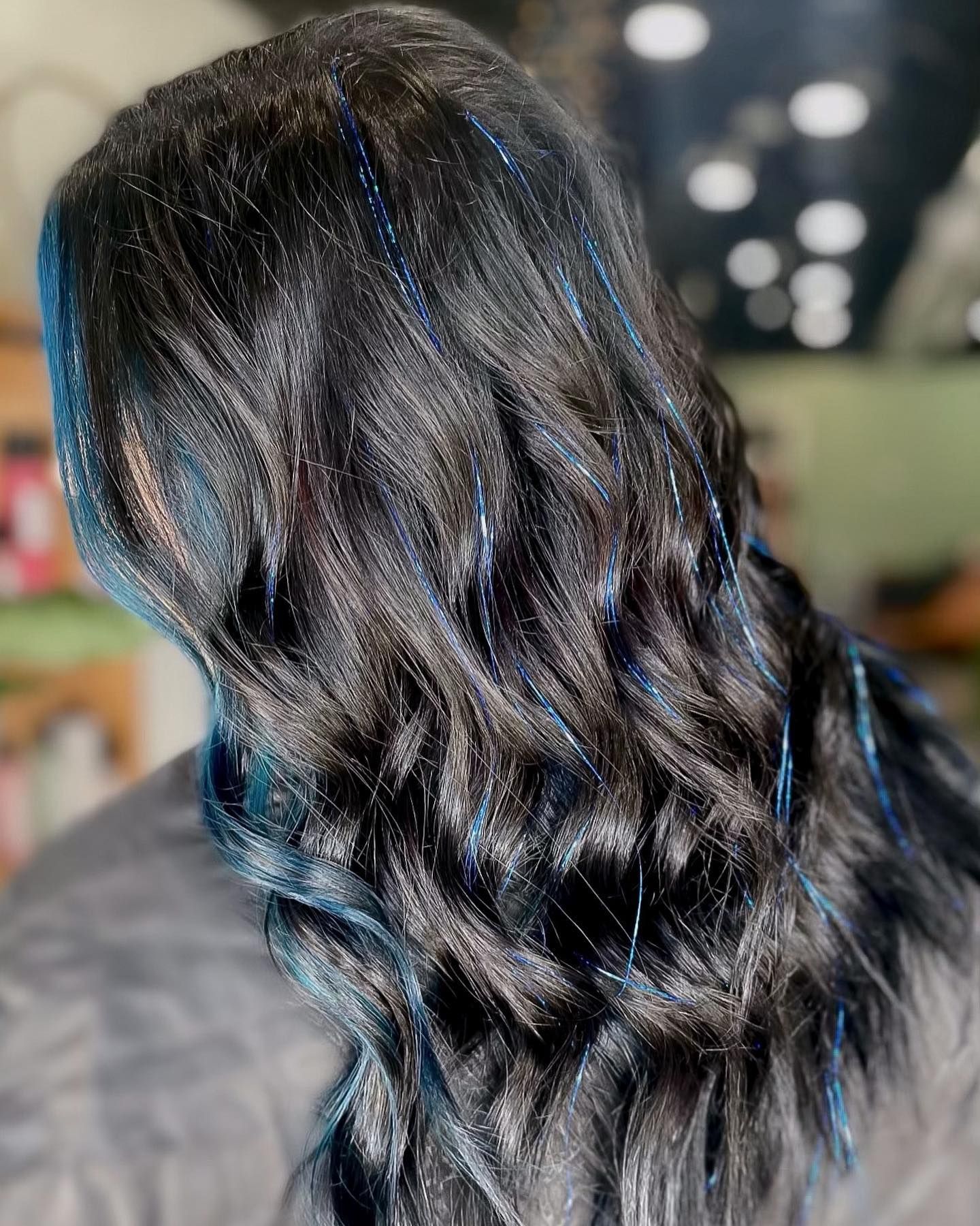 Long, wavy black hair with thin strands of blue glitter.