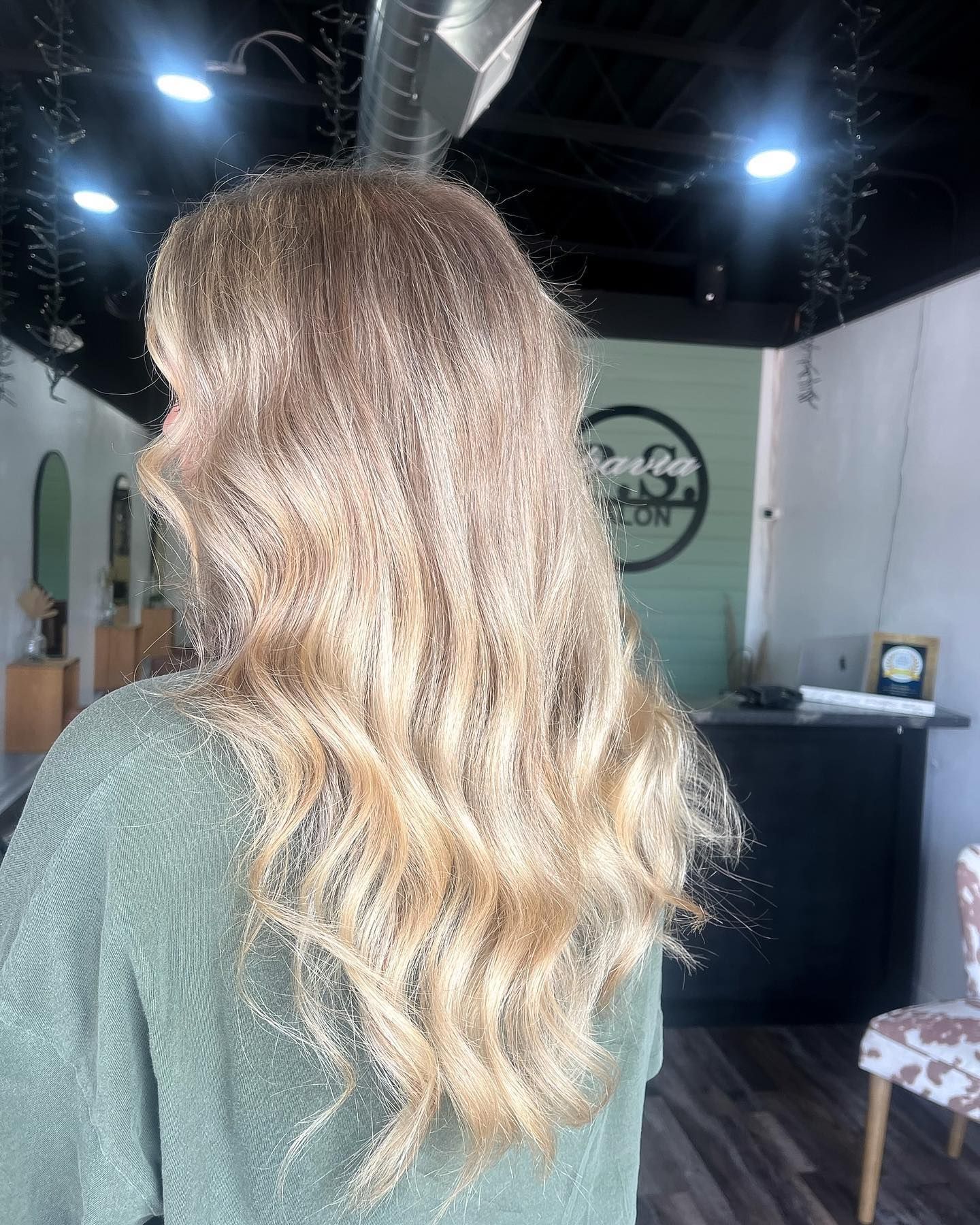 Blonde hair styled in loose waves, client in salon setting.