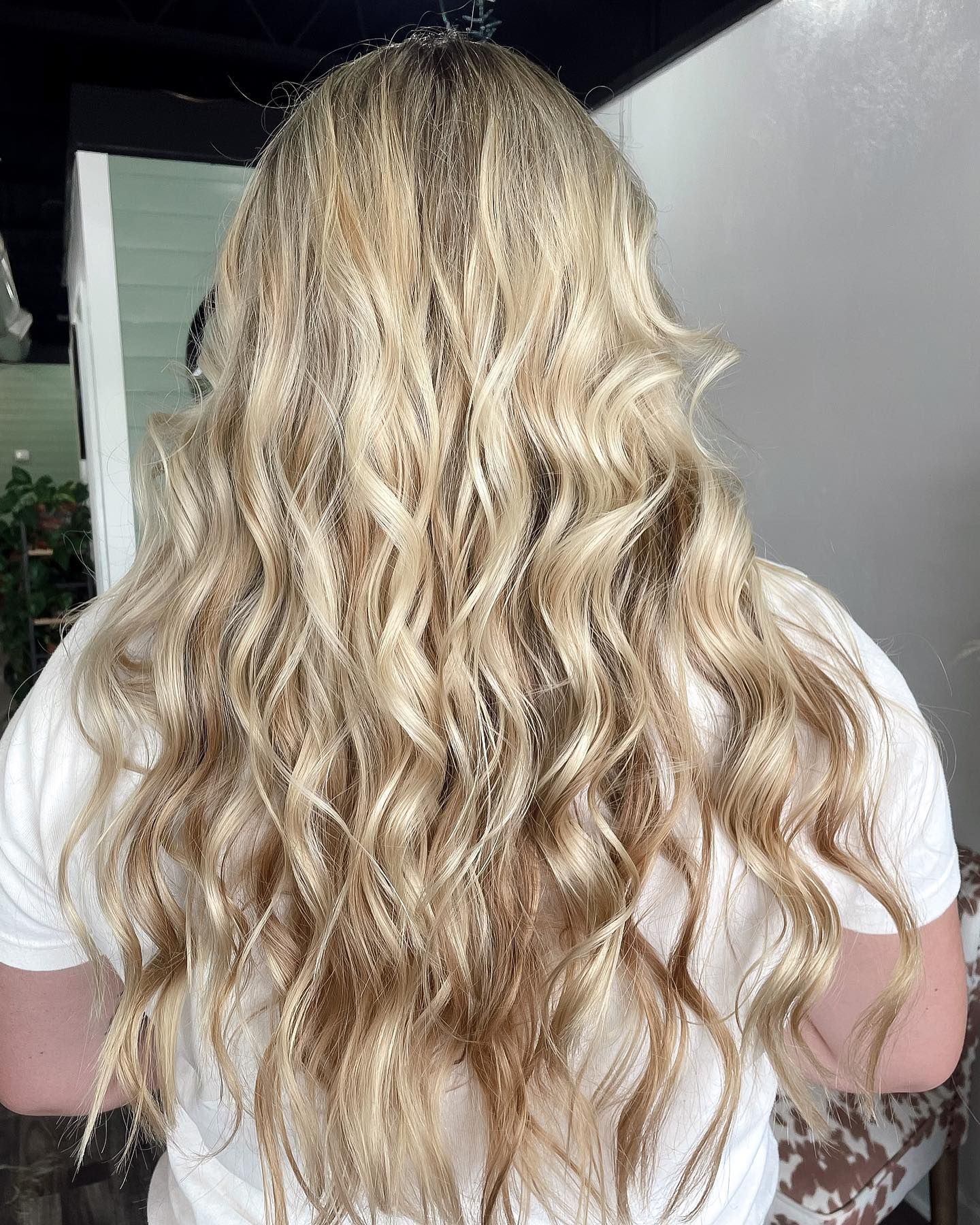 Woman with long, wavy blonde hair wearing a white t-shirt.