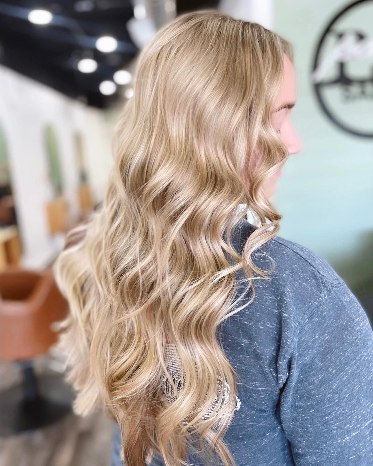 Woman with long, wavy, blonde hair styled in a salon setting.