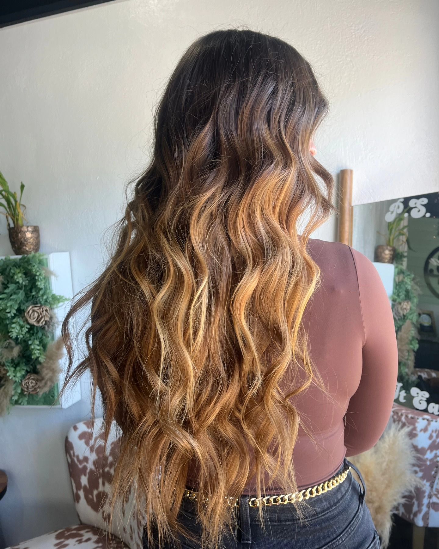 Woman with long, wavy, ombre brown to blonde hair, in a salon setting.
