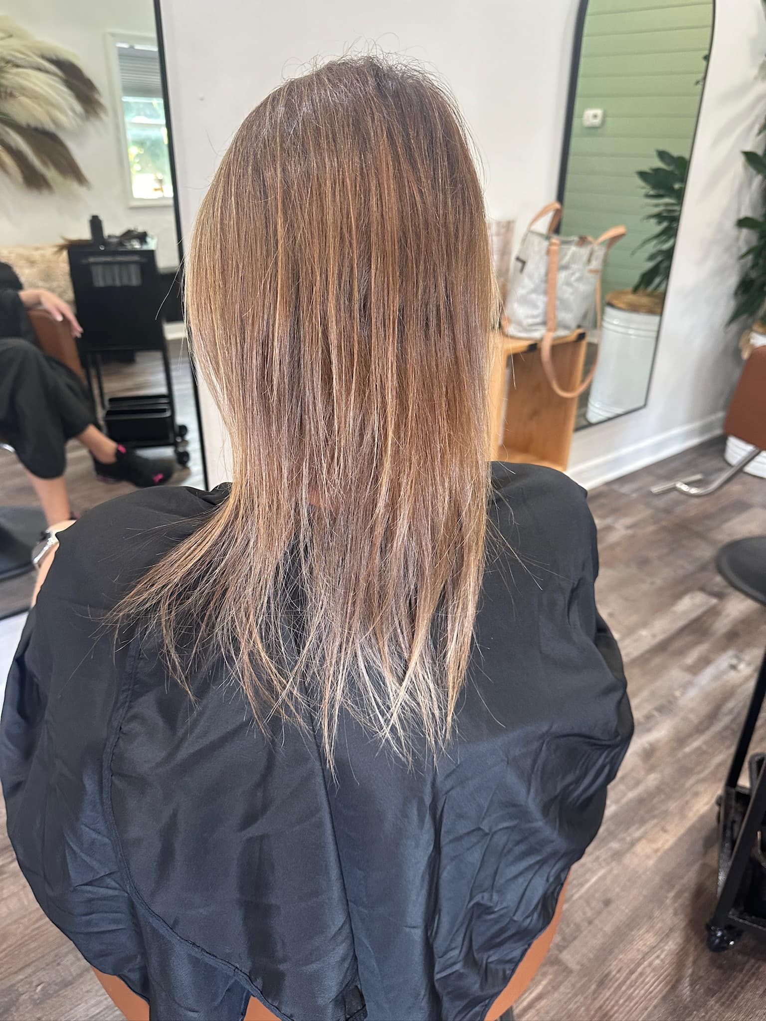 Person in black salon cape, wet hair with bleach, in salon.