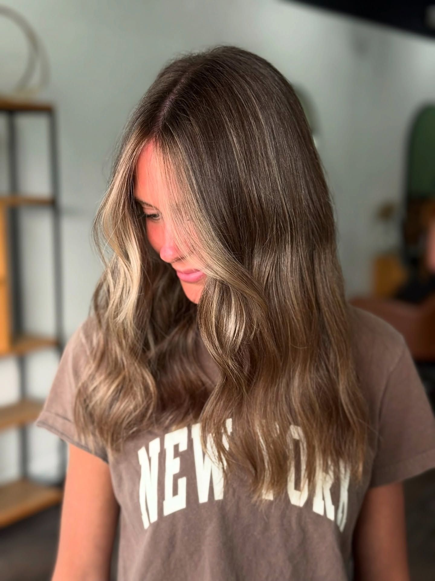 Woman with wavy highlighted hair wearing a brown 