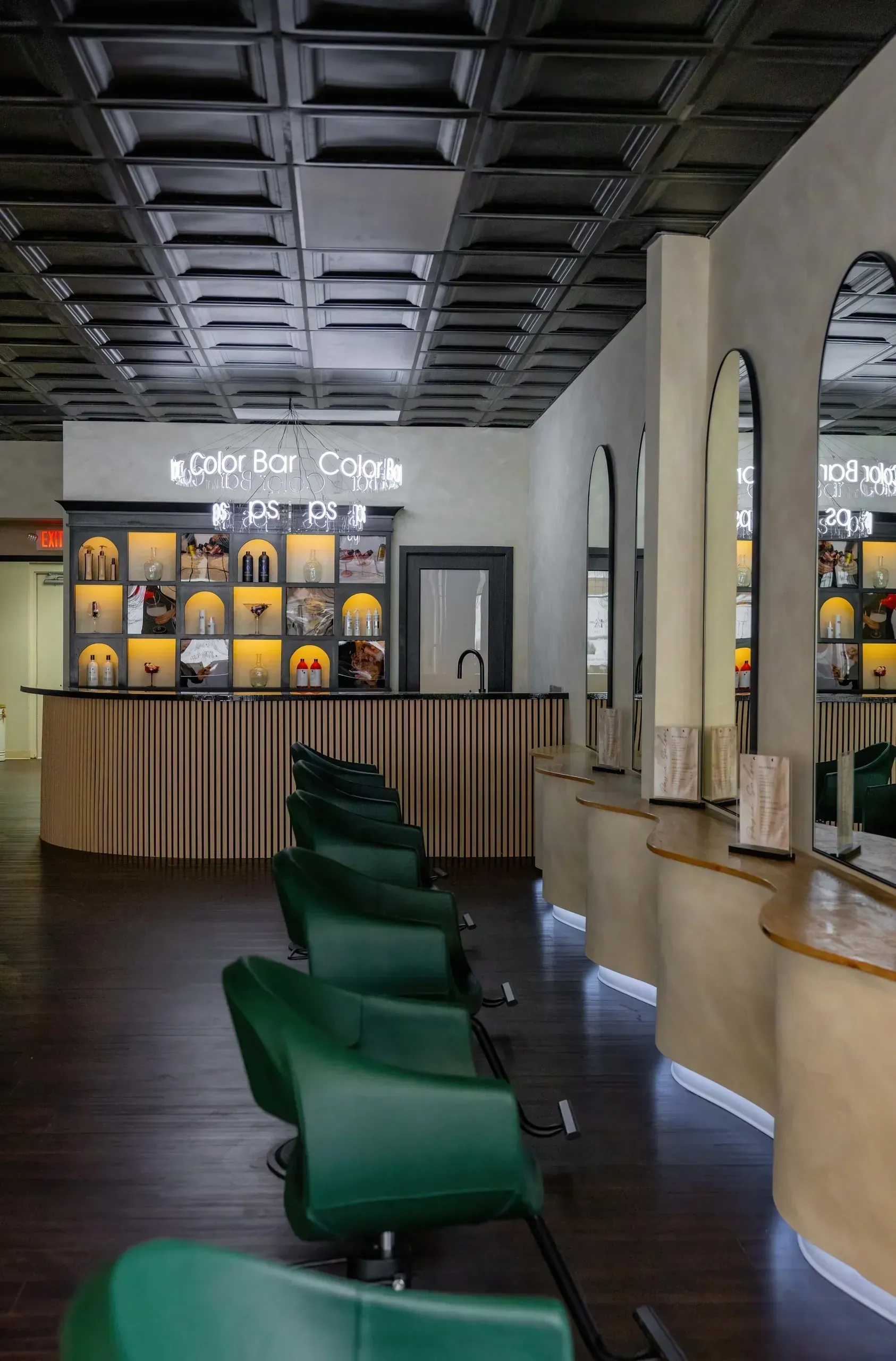 Hair salon interior with green chairs, arched mirrors, and ornate ceiling.