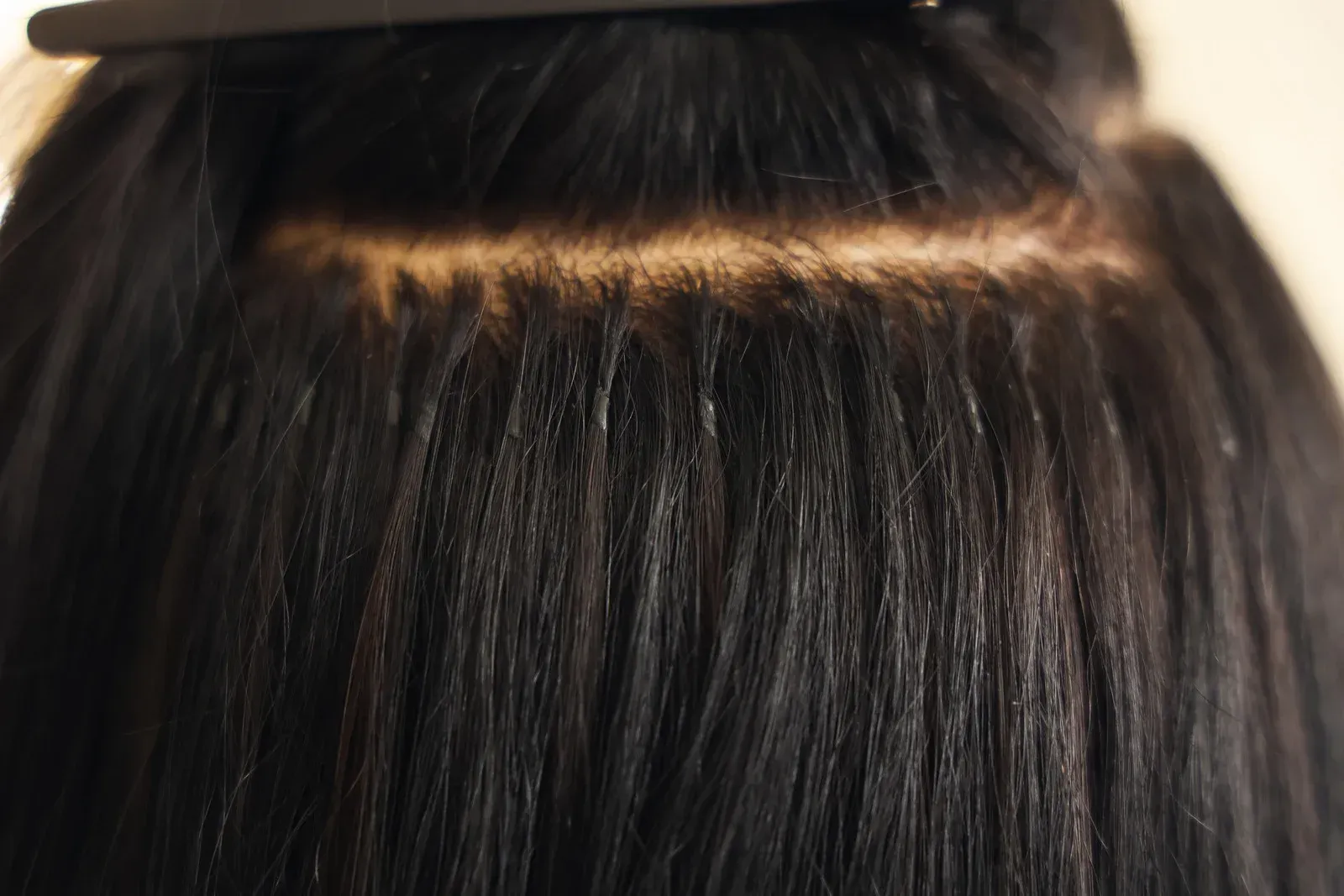 Dark hair with hair extensions visible at the scalp, held back with a clip.