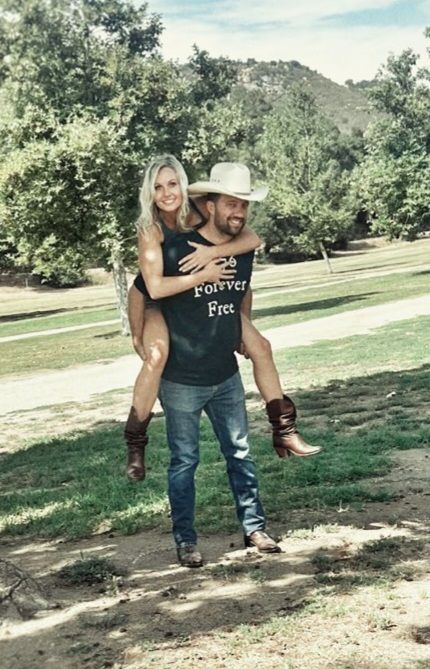 A man is carrying a woman on his back in a park.