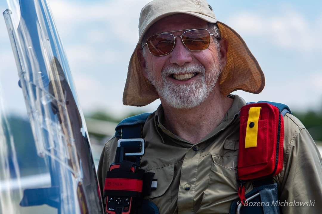 John, CFI, instructor wearing a hat and sunglasses is holding an airplane.