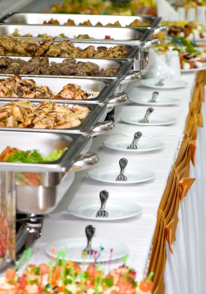 A long buffet table filled with lots of food and plates.
