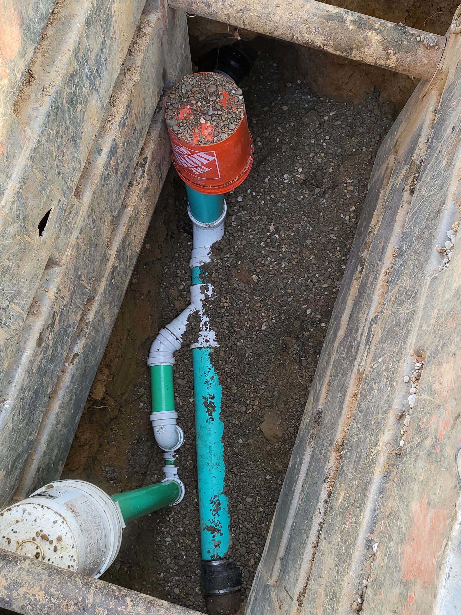 Construction worker repairing a broken water pipe on a concrete road.