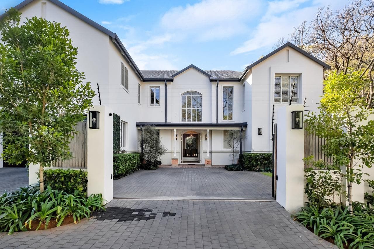 A large white house with a brick driveway leading to it