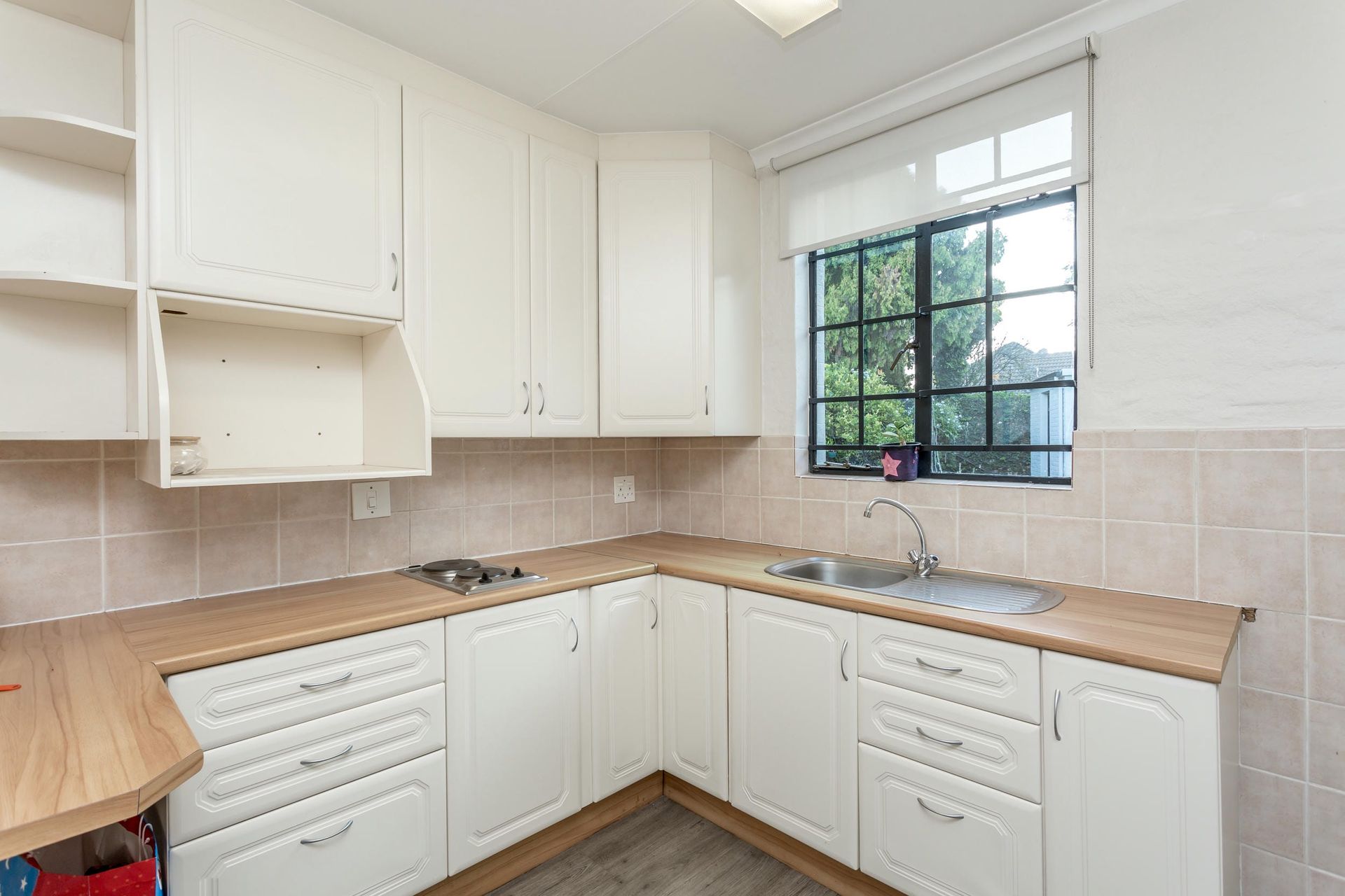 An empty kitchen with white cabinets and a window