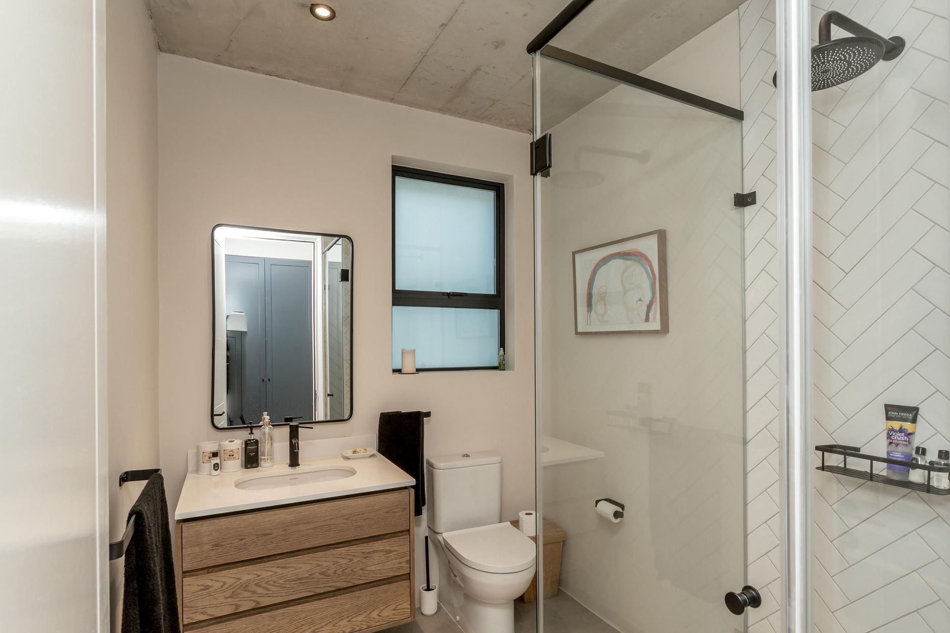 A bathroom with a toilet , sink and shower.