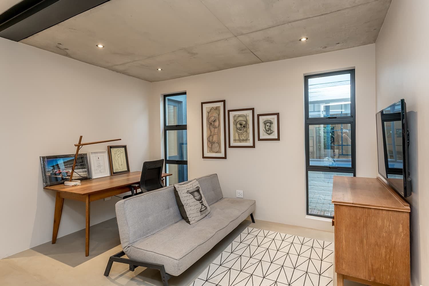 A living room with a couch , desk and television.