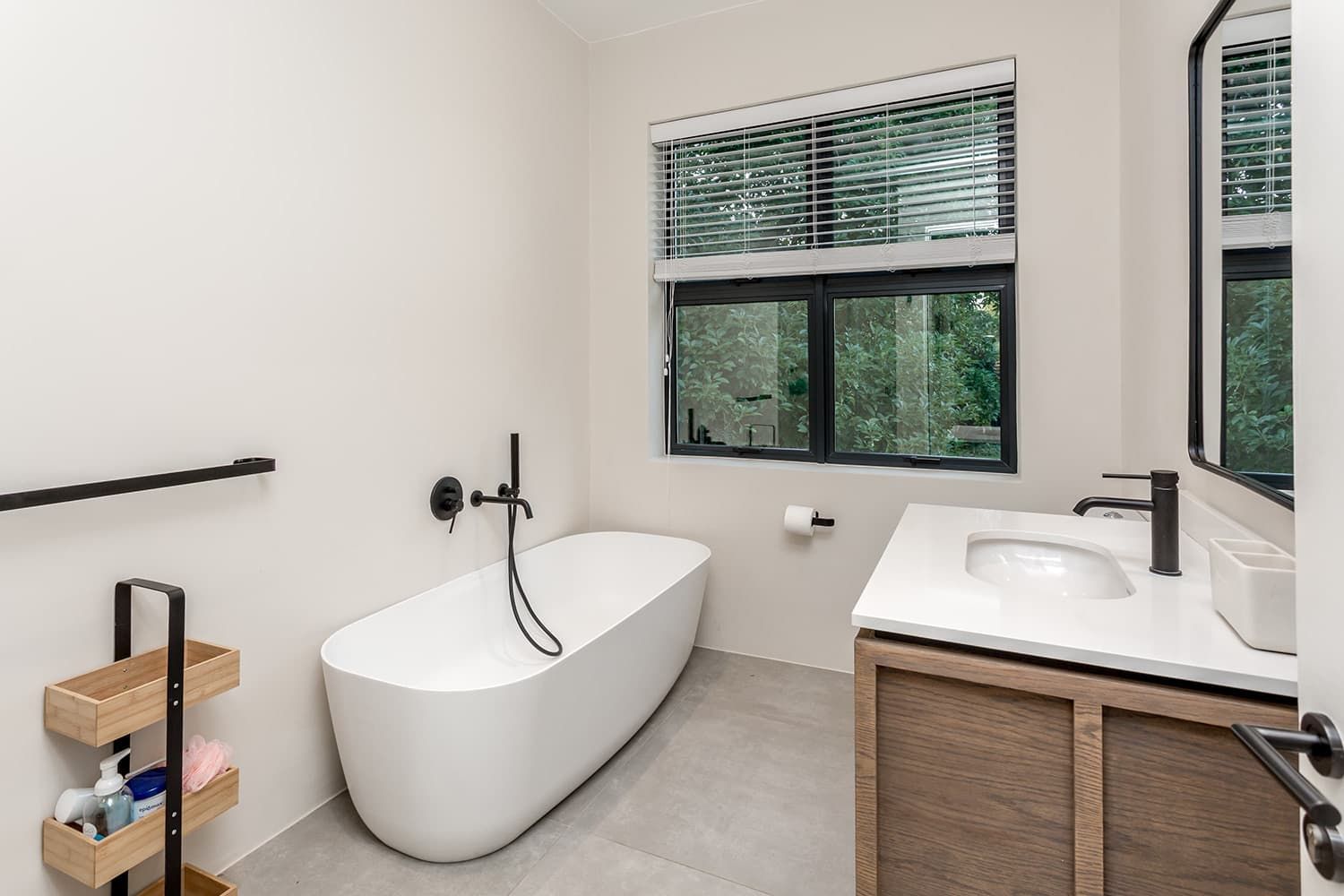 A bathroom with a tub , sink , mirror and window.