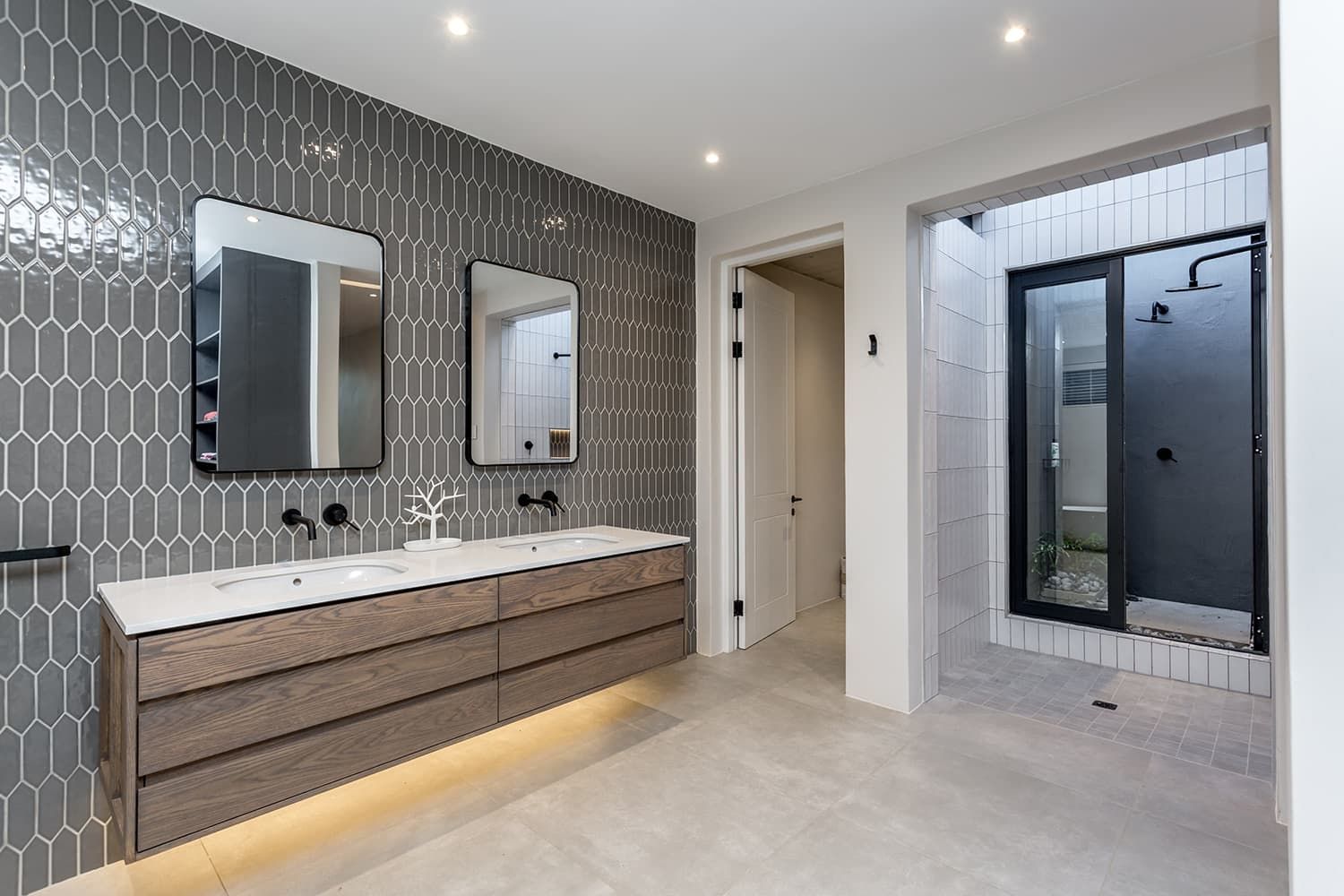 A bathroom with two sinks , two mirrors and a walk in shower.