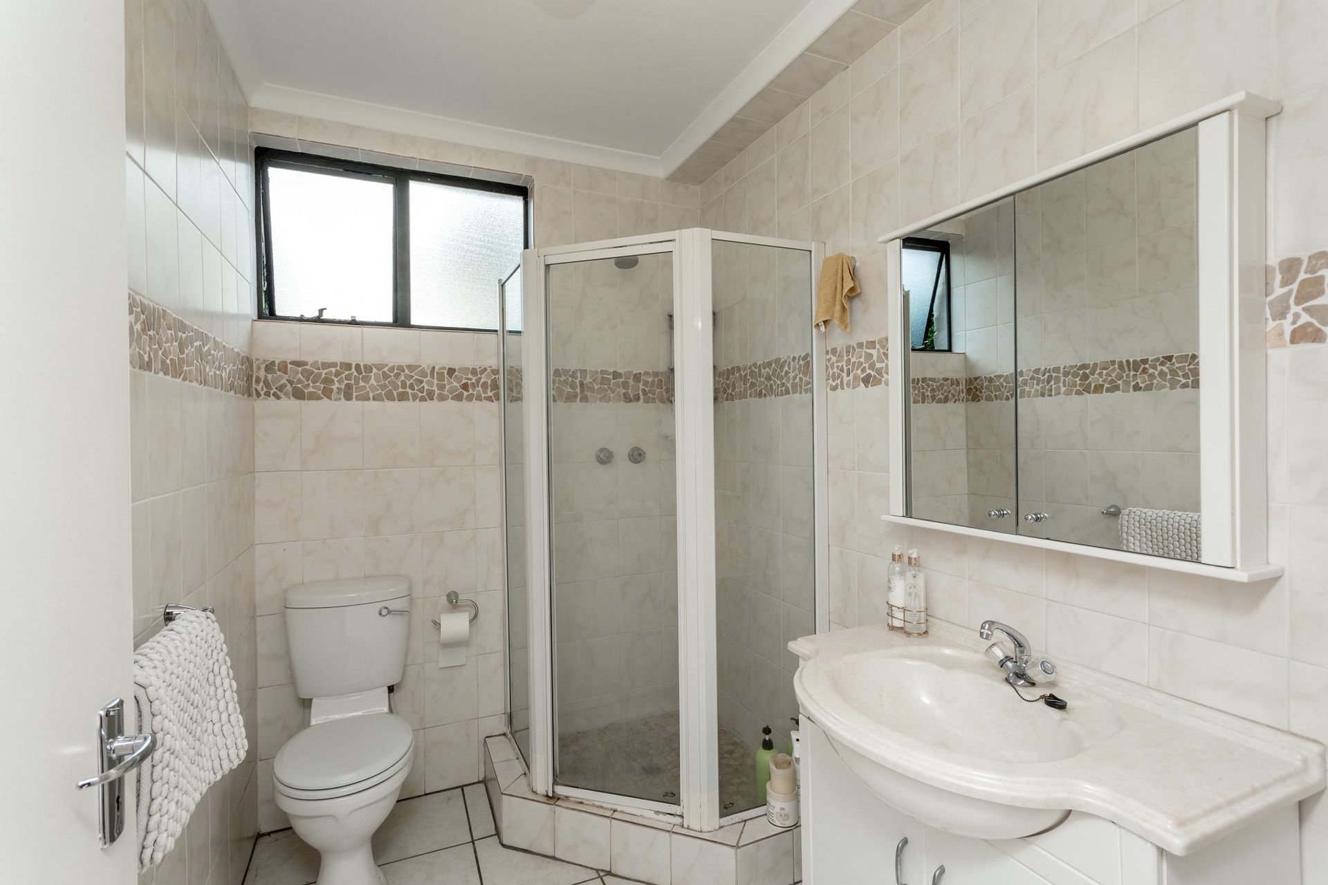 A bathroom with a toilet , sink and shower.