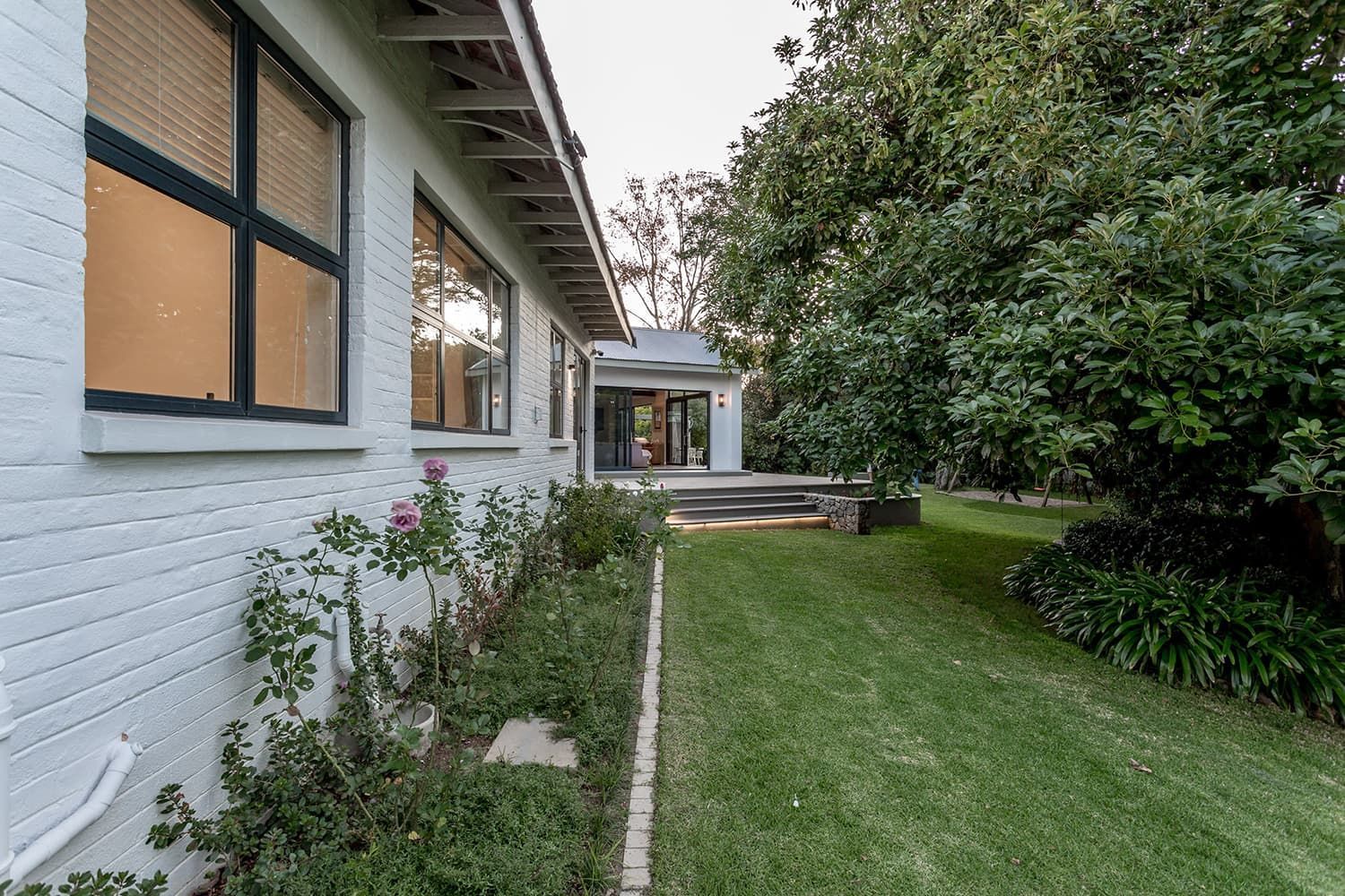 A white brick house with a large lawn in front of it