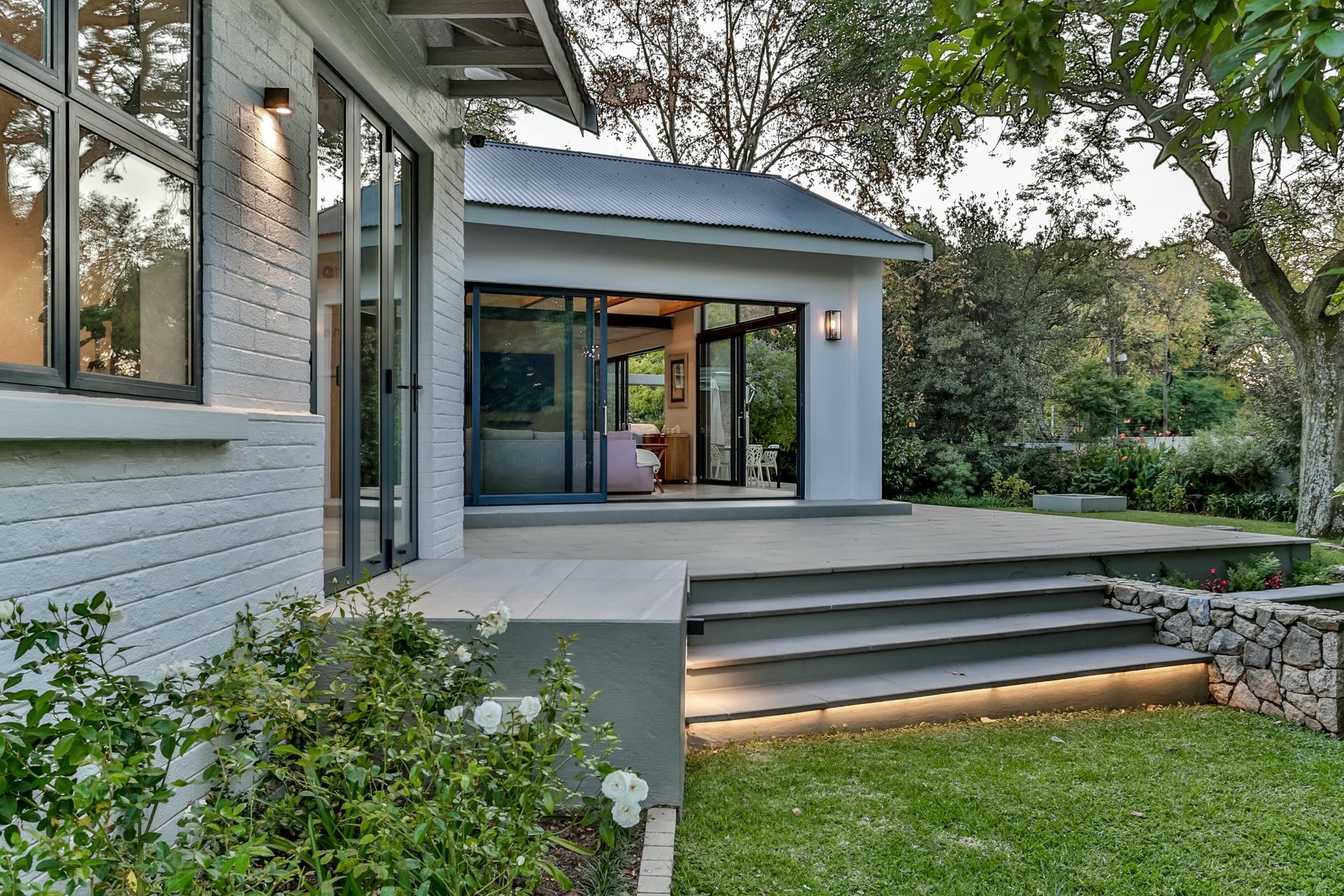 A white house with a sliding glass door and stairs leading to it.